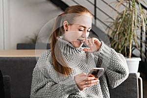 Portrait of a beautiful teenager relaxing and using a mobile phone to have a conversation with friends, smiling and