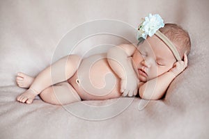 Portrait of beautiful ten days old newborn baby girl wearing flower headband.