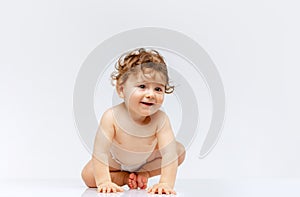 Portrait of beautiful toddler boy, baby in diaper crawling isolated over white studio background. Happy child