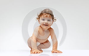 Portrait of beautiful toddler boy, baby in diaper crawling isolated over white studio background. Happy child
