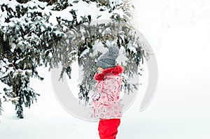 Portrait of a beautiful toddler girl playing outdoors with snow. Happy little child enjoying a winter day in the park or