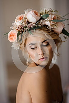 Portrait of the beautiful topless blonde woman in a floral wreath with closed eyes