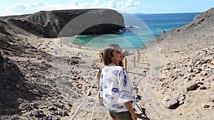 Portrait of beautiful tourist woman with Playa Papagayo landscape on background. Happy girl on Lanzarote island with Playa Papagay
