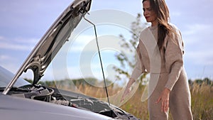 Portrait of beautiful troubled woman checking broken car engine hitting hood sighing. Anxious dissatisfied Caucasian