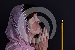 Portrait of beautiful Ukrainian woman praying in front of candle