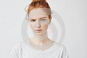 Portrait of beautiful upset redhead girl looking at camera.