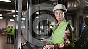 Portrait of Beautiful Warehouse Worker Woman Sitting in Forklift Looking at Camera