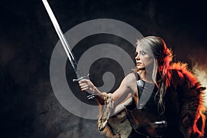 Portrait of a beautiful warrior woman holding a sword wearing steel cuirass and fur. Fantasy fashion. Cosplayer as Ciri