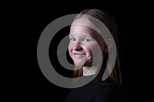 Portrait of beautiful white girl with freckles on dark black background. Close up portrait of happy smiling girl.