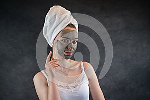 Portrait of beautiful Woman applying nourishing green clay mud mask to her face isolated on black