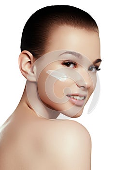 Portrait of beautiful woman applying some cream to her face for skin care