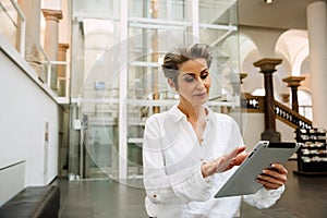 Portrait of beautiful woman art gallery manager using tablet while standing in museum