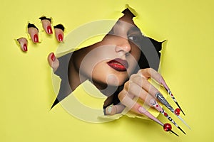 Portrait of a beautiful woman with art make up in glamorous style, creative long nails on a yellow background . Design