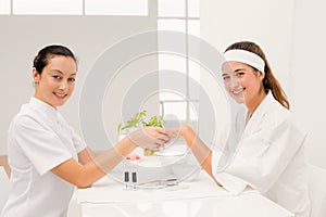 Portrait beautiful woman with beautician applying nail varnish to female clients nails