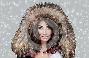 Portrait of a beautiful woman with beautiful make-up and manicure in a fur coat on a background of snow