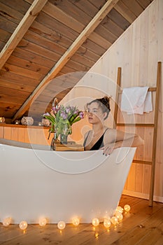 Portrait of beautiful woman in black underwear relaxing and spending weekend at home. Taking bath with glass of wine on