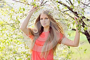 Portrait of beautiful woman in blooming tree in spring