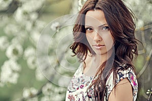 Portrait of beautiful woman in blooming tree in spring