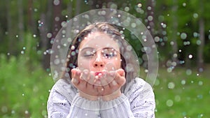 Portrait of beautiful woman blowing confetti glitter off hands outdoors