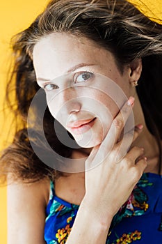 portrait of a beautiful woman in a blue floral dress on a yellow background