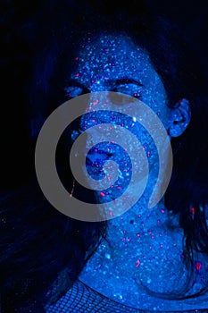 Portrait of a beautiful woman with blue sequins on her face. Girl with artistic make-up in Light color. Fashion model