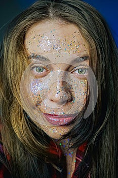 Portrait of a beautiful woman with blue sparkles on her face. Girl with colorful artistic make-up with glitter. Fashion