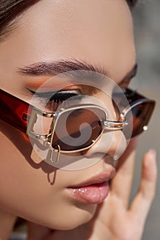 Portrait of a beautiful woman with bright red makeup and dark sunglasses close-up. Red shadows on the eyes of a girl, professional