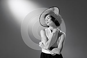 Portrait of beautiful woman in character of famous fashion designer posing in stylish classic suit. Black and white