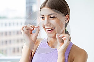 Portrait of beautiful woman cleaning teeth with dental floss