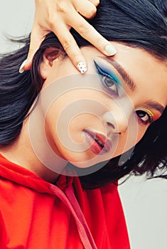 Portrait of a beautiful woman with colorful nails, amazing makeup and dark hairs on white background