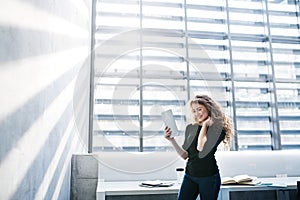 Portrait of beautiful woman with curly hair holding tablet in hand.