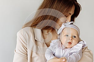 Portrait of beautiful woman with cute newborn baby girl in studio. Loving mother hold adorable little daughter in arms