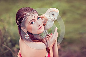Portrait of beautiful woman in diadem with owl on her hand