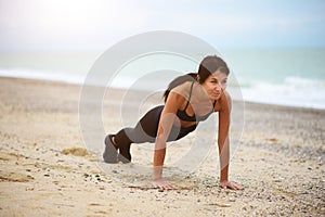 A portrait of beautiful woman doing push-ups on the beach.