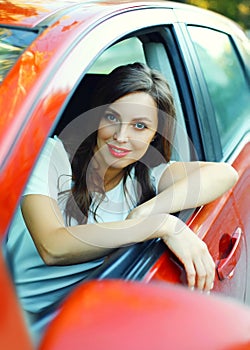 Portrait beautiful woman driver behind wheel red car