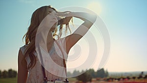 Portrait of beautiful woman enjoying sun in summer day. Pretty girl playing hair