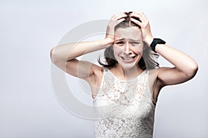 Portrait of beautiful woman with freckles and white dress and smart watch with headache pain on silver gray background.