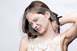 Portrait of beautiful woman with freckles and white dress and smart watch with neck pain on silver gray background.