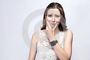 Portrait of beautiful woman with freckles and white dress and smart watch with tooth pain on silver gray background.