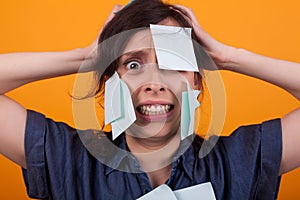 Portrait of beautiful woman frustrated with sticky notes on forehead in studio over yellow background