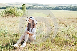 portrait of a beautiful woman in a hat in a field in nature