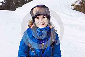Portrait of beautiful woman in helmet and mask, snowboard suit in winter mountain