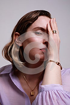 Portrait of beautiful woman with a high hairstyle is wearing a purple top. Big golden shine earrings jewellery.