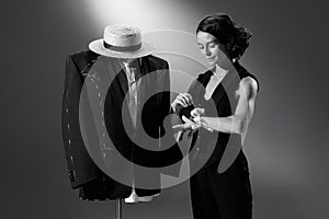 Portrait of beautiful woman in image of famous fashion designer working on male classic suit. Black and white