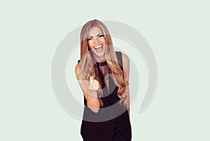 Portrait of a beautiful woman laughing ecstatic pointing at you isolated on light green