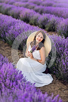 Portrait of a beautiful woman in lavender. A girl in a white sundress and hat in the summer in nature