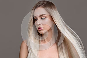 Portrait of a beautiful woman with long straight hair and makeup. Flying blonde hair