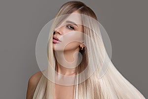 Portrait of a beautiful woman with long straight hair and makeup. Flying blonde hair