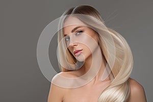 Portrait of a beautiful woman with long straight hair and makeup. Flying blonde hair