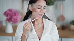 Portrait of beautiful woman makes makeup and use brush to put powder on her face